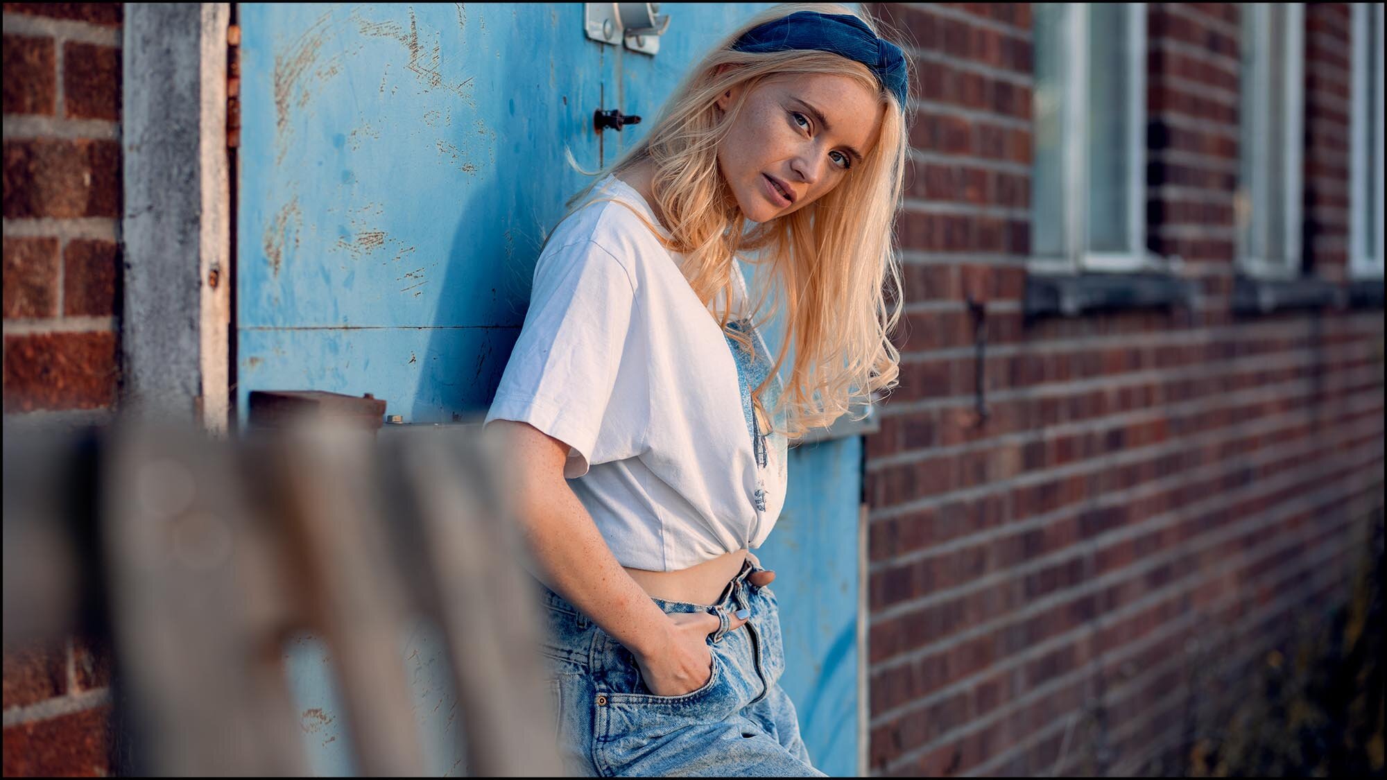 Blonde woman leaning against a blue door