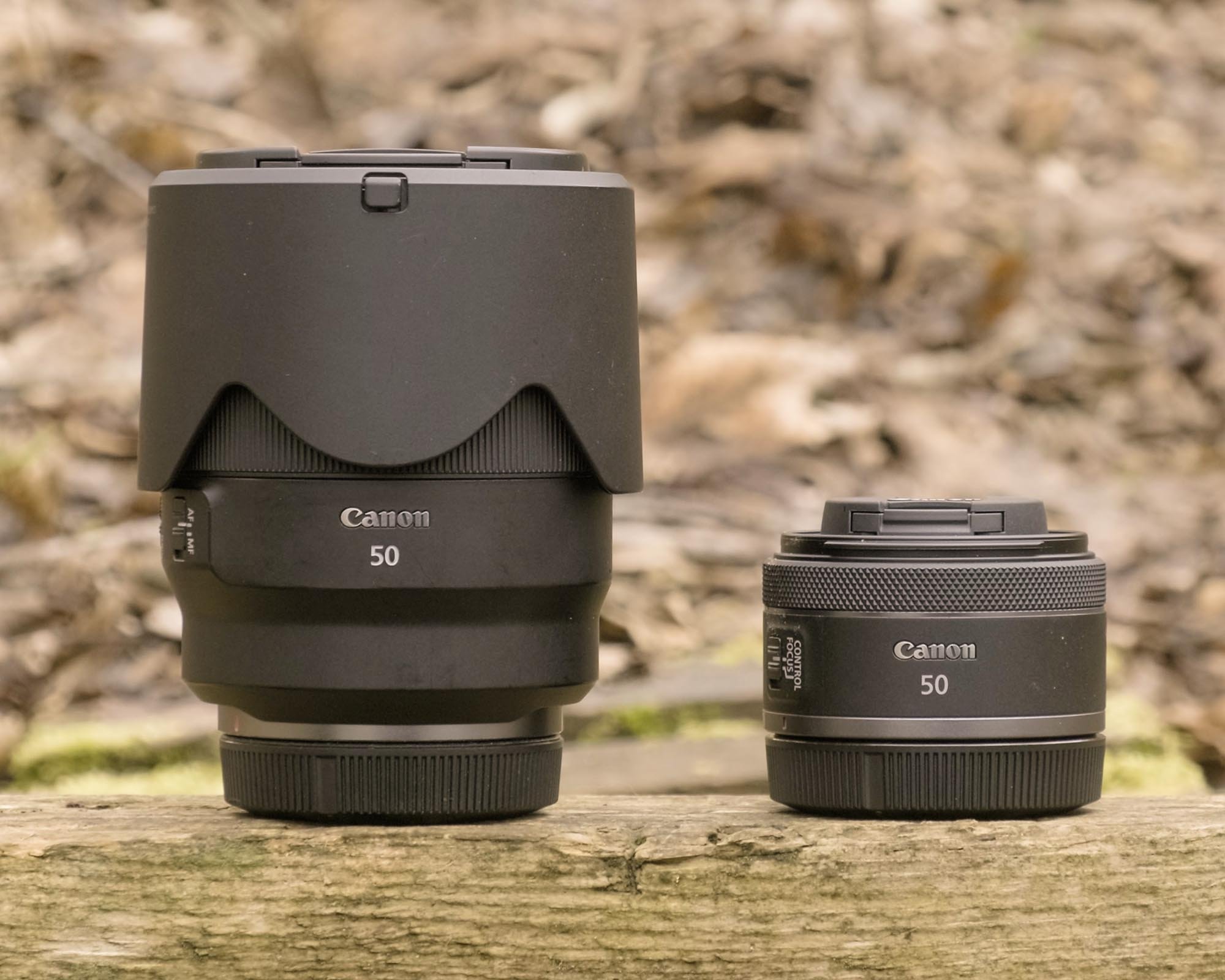 Two Canon 50mm lenses sitting side-by-side on a wooden surface. The larger lens is the 50mm f/1.2 and the smaller is the 50mm f1.8.
